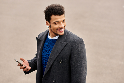 Charming man smiles as he uses his smartphone while standing in an urban setting