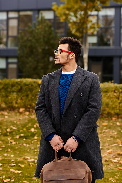 A well dressed man stands confidently in a park surrounded by vibrant autumn leaves.