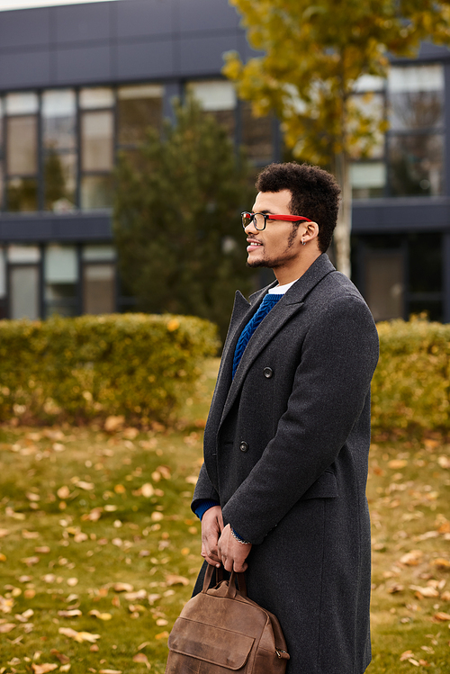 A charming man stands quietly in a park, embracing the beauty of the fall season.