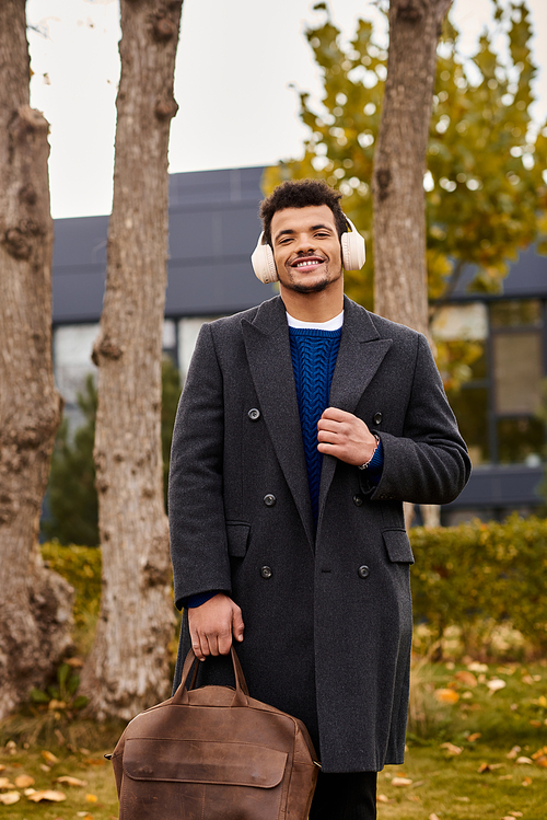 A stylish man smiles while walking through an autumn landscape, dressed for the cool weather.