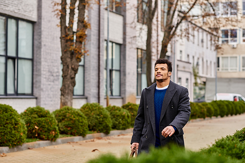 A dapper man walks confidently down the tree lined street, enjoying the crisp air.