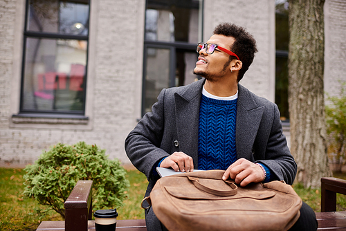 Charming gentleman sits on a bench, smiling while holding a bag in a bustling park.