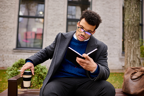 Gentleman absorbed in reading a book, sipping coffee on a sunny day in a serene park.