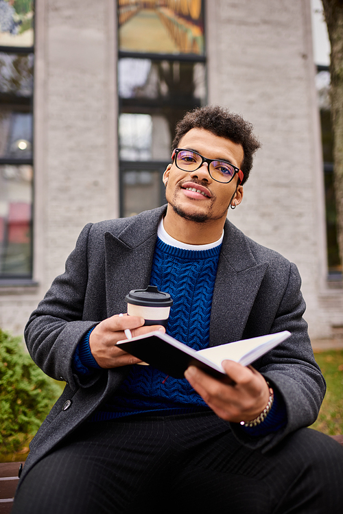 A stylish individual sits comfortably on a bench, savoring a beverage and reading a book.