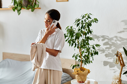 A young african american woman cleans and chats on the phone in her modern apartment.