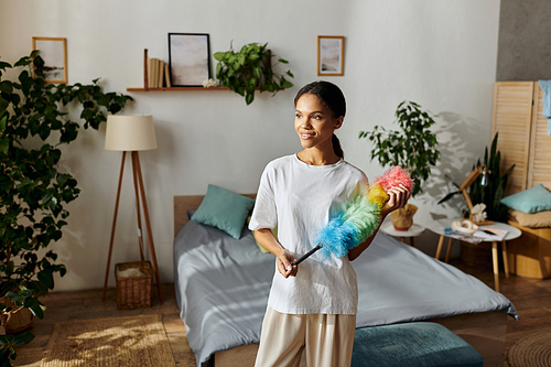 A happy young woman smiles while cleaning her stylish apartment.