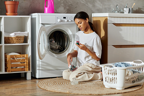 A young African American woman cleans and organizes laundry in a chic apartment.