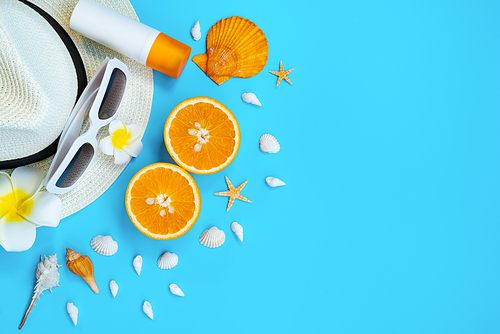 Beautiful summer holiday, Beach accessories, sunglasses, hat, orange, sunblock and shells on blue backgrounds