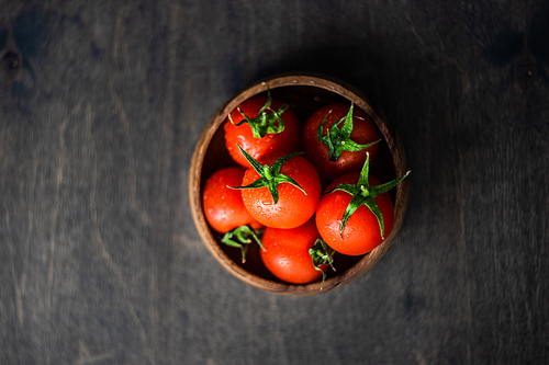 organic fresh cherry tomatoes in a bowl on rustic background with copy space
