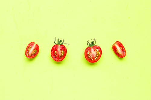 Fresh tomatoes, half cut isolated on green background. Top view