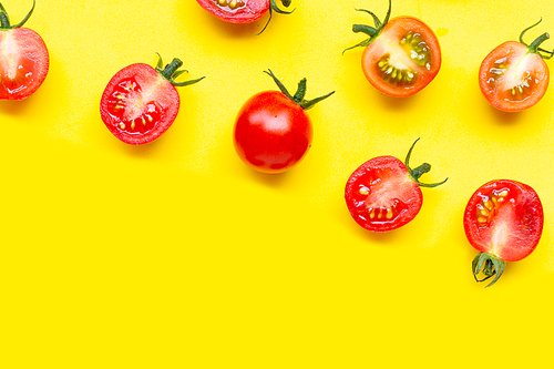 Fresh tomatoes, whole and half cut isolated on yellow background. Top view