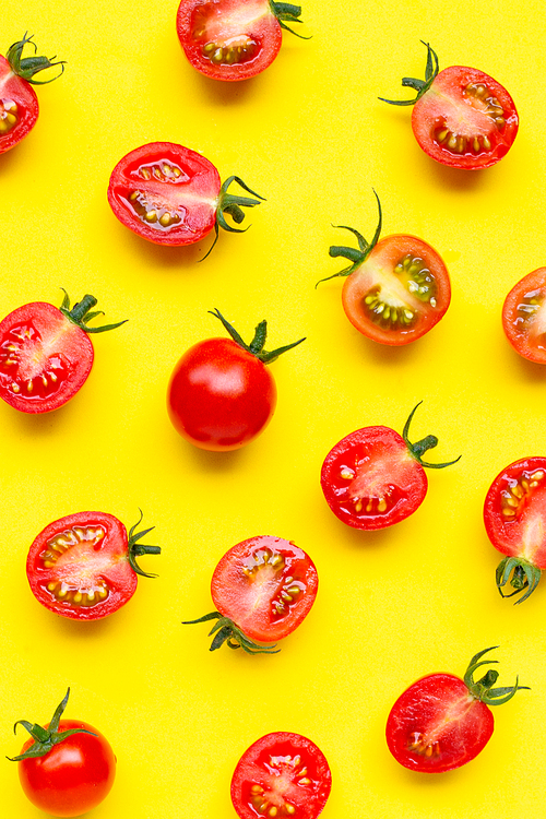 Fresh cherry tomatoes, whole and half cut isolated on yellow background. Top view