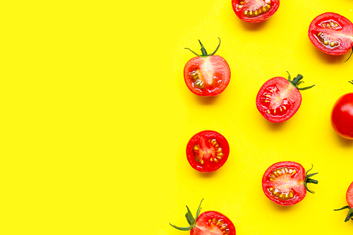 Fresh cherry tomatoes, whole and half cut isolated on yellow background. Copy space