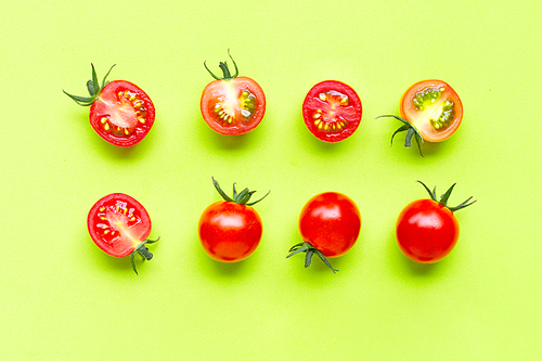 Fresh cherry tomatoes, whole and half cut isolated on green background. Top view