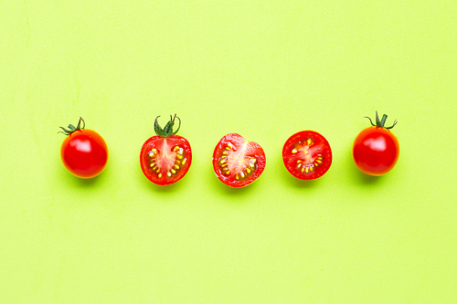 Fresh  cherry tomatoes, whole and half cut on green background. Top view