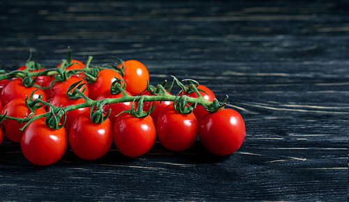 Cherry tomatoes on the dark wooden table. Juicy ripe vegetables on a black background. Healthy eating. vegetarian food