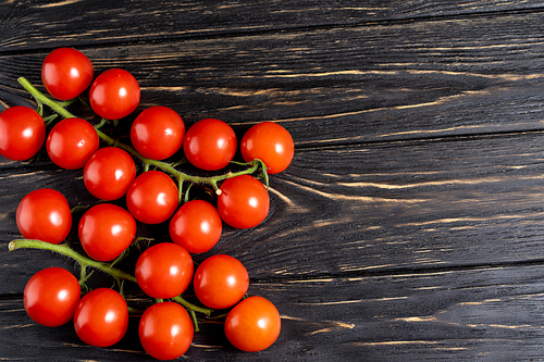 Cherry tomatoes on the dark wooden table. Juicy ripe vegetables on a black background. Healthy eating. vegetarian food