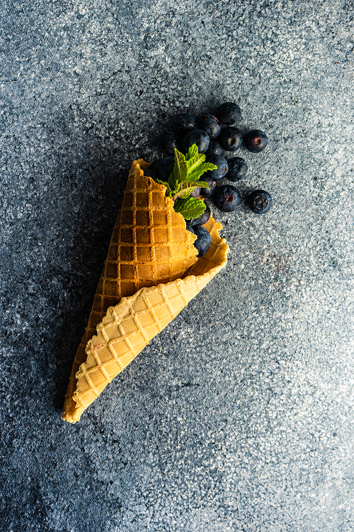 Organic blueberry fruits in waffle cone on concrete background with copy space