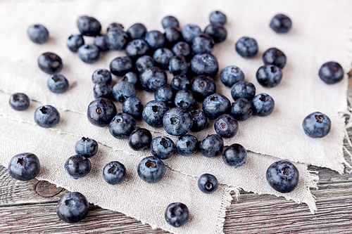 blueberries lie on homespun tablecloth. rustic cozy background with healthy food. fresh-gathered berries full of vitamins, good for  nutrition and healthy meals.