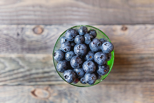 fresh blueberries in glass bowl. fresh wet berries on rustic wooden background. fresh-gathered berries full of vitamins, good for  nutrition and healthy meals.