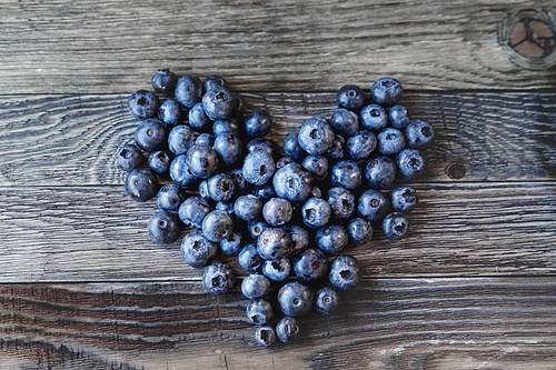 blueberries on rustic wooden cozy background. fresh-gathered berries full of vitamins, good for  nutrition and healthy meals. heart as a symbol of love and romance.