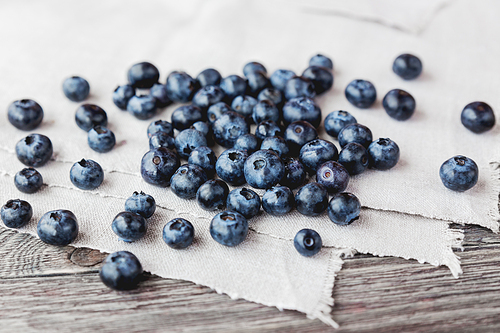 Blueberries lie on homespun tablecloth. Rustic cozy background with healthy food. Fresh-gathered berries full of vitamins, good for diet nutrition and healthy meals.