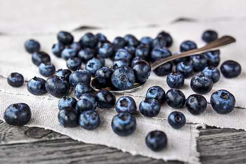 blueberries lie on a homespun tablecloth and in metal spoon. rustic cozy background with healthy food. fresh-gathered berries full of vitamins, good for  nutrition and healthy meals.