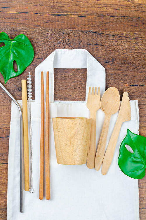 Zero waste concept. Textile eco bags, wooden glass and bamboo utensil on wooden background. Eco friendly and reuse concept. Top view or flat lay