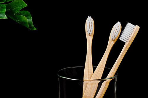 Bamboo toothbrushes with green leaves on black background, Zero waste concept.