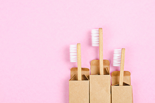 Bamboo toothbrushes on pink background with free space for your text or message.