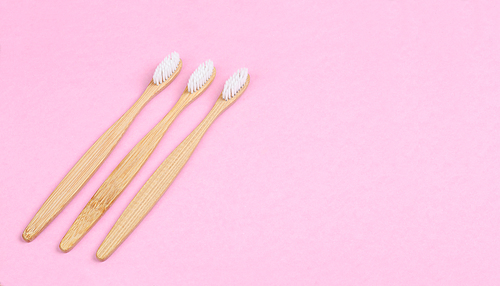 Bamboo toothbrushes on pink background with free space for your text or message.