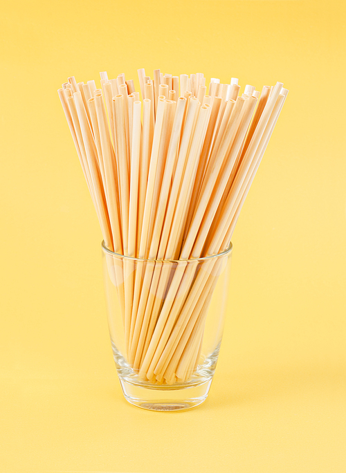 wheat straws for  water natural eco friendly renewable in glass on yellow background.