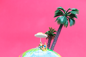 Miniature people wearing swimsuit relaxing on The globe with pink background , Valentine's day concept