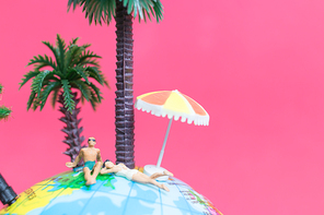 Miniature people wearing swimsuit relaxing on The globe with pink background , Valentine's day concept