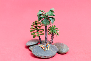 Miniature people wearing swimsuit relaxing on the rock with pink background , Valentine's day concept