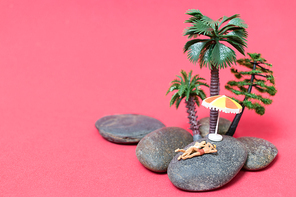 Miniature people wearing swimsuit relaxing on the rock with pink background , Valentine's day concept