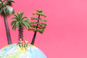 Miniature people wearing swimsuit relaxing on The globe with pink background , Valentine's day concept