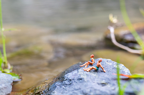 Miniature people wearing swimsuit sunbathing on a rock  , Travel  concept