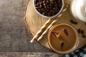 Iced coffee or caffe latte in tall glass on wooden table.