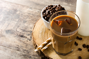 Iced coffee or caffe latte in tall glass on wooden table.