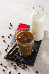 Iced coffee or caffe latte in a tall glass on wooden table