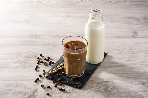 Iced coffee or caffe latte in a tall glass on wooden table