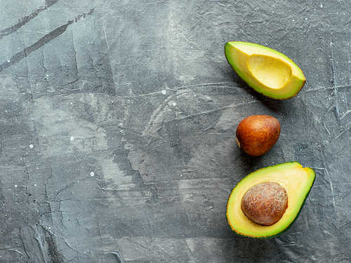 Avocado with copy space. Top view of avocado half, quarter and avocado pit on gray background. Food background