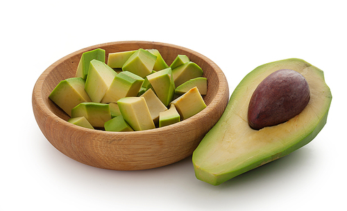Half avocado with pit and avocado cuves in wooden bowl