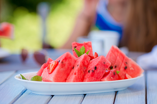 Tasty slices of watermelon on white plate on a wooden background