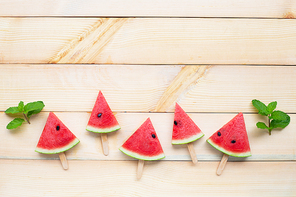 Watermelon slice popsicles on wooden background. Copy space