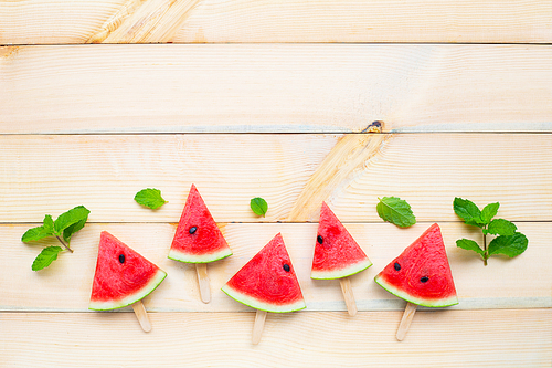 Watermelon slice popsicles on brown wooden background. Top view