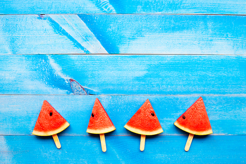 Watermelon slice popsicles on blue wooden background. Top view