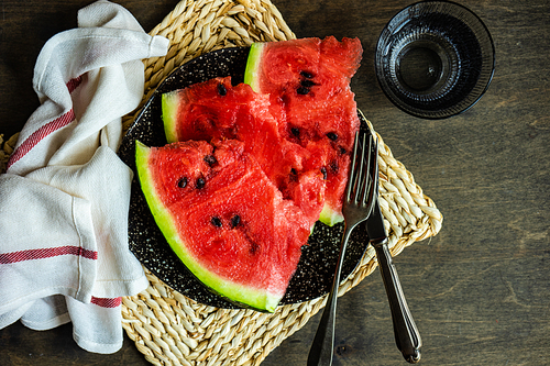 Ripe organic watermelon slices on a plate as a summer dessert on wooden table
