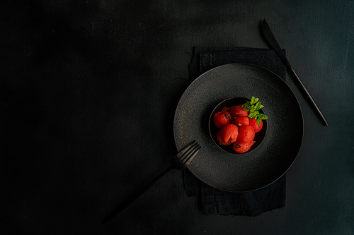 Served summer dessert with watermelon balls and mint in black stoneware on black background